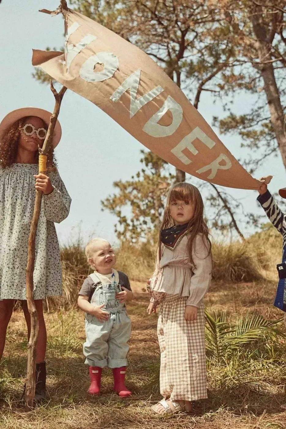 Children under a hand-made WONDER banner in the bush